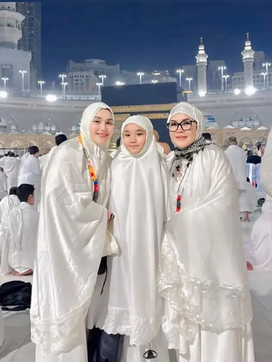 Sampai di depan Ka'bah, ia pun mengenakan mukena putih shimmer dengan renda. Serasi dengan putrinya, Bilqis dan ibunda tercinta. [@ayutingting92]
