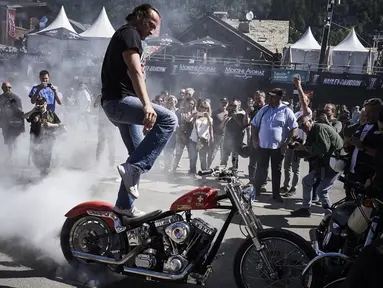 Seorang pria melakukan aksi berdiri diatas motor saat acara 6th Morzine-Avoriaz Harley Days 2017, Morzine (15/7). Sekitar 10.000 sepeda motor dan 30.000 bikers dari seluruh Eropa berkumpul untuk mengikuti acara ini. (AFP Photo/Jean-Philippe Ksaizek)