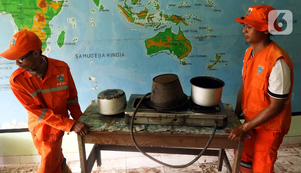 Petugas memindahkan barang-barang saat membersihkan ruangan di MTsN 19 Pondok Labu, Jakarta, Jumat (7/10/2022). Petugas PPSU, Satpol PP, dan Dinas Pemadam Kebakaran membersihkan ruang kelas, kantin, dan fasilitas lainnya usai terendam banjir pada Kamis sore kemarin. (Liputan6.com/Herman Zakharia)