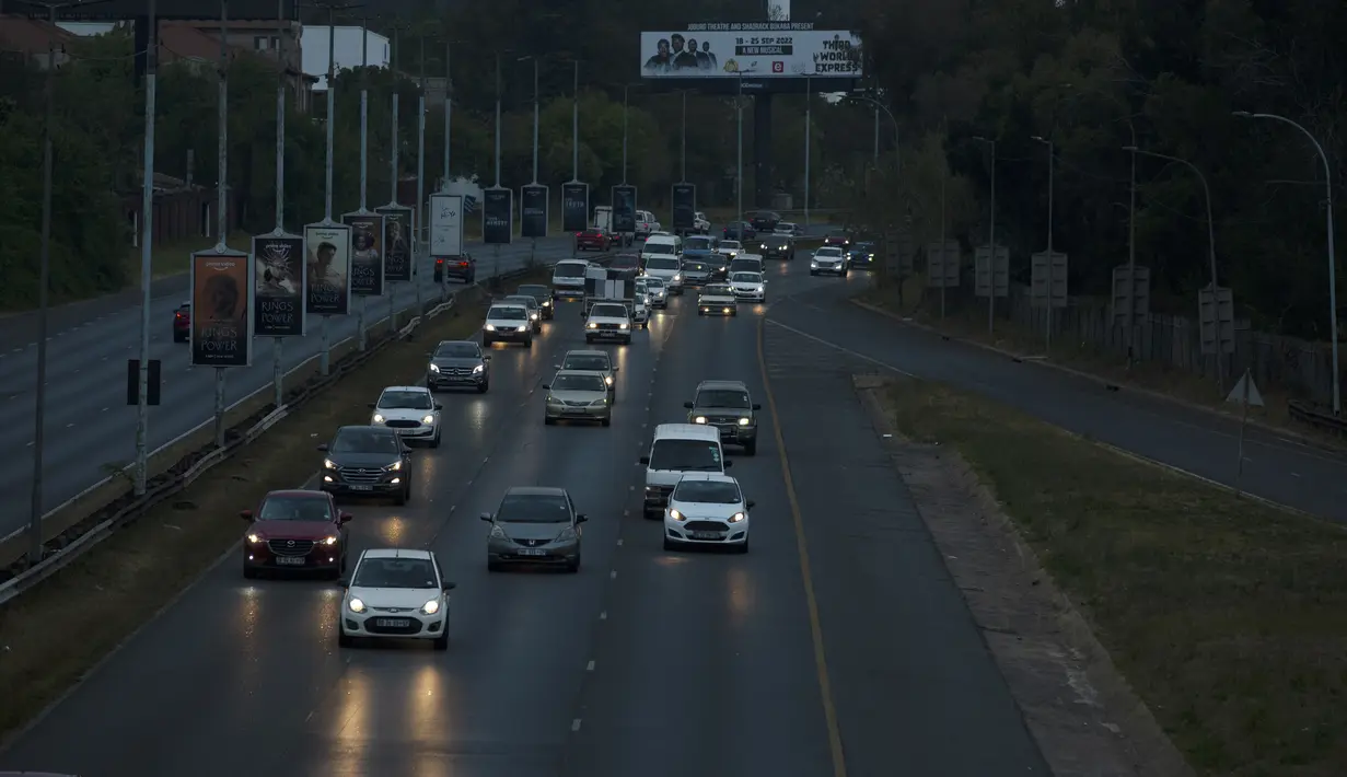 Mobil berjalan di bagian jalan bebas hambatan yang biasanya cukup terang selama pemadaman listrik di Johannesburg, Rabu, 21 September 2022.  Warga diminta berhemat, dengan mematikan pompa kolam renang serta pemanas air di jam sibuk, dan kantor didesak mematikan listrik di malam hari. (AP Photo/Denis Farrell)