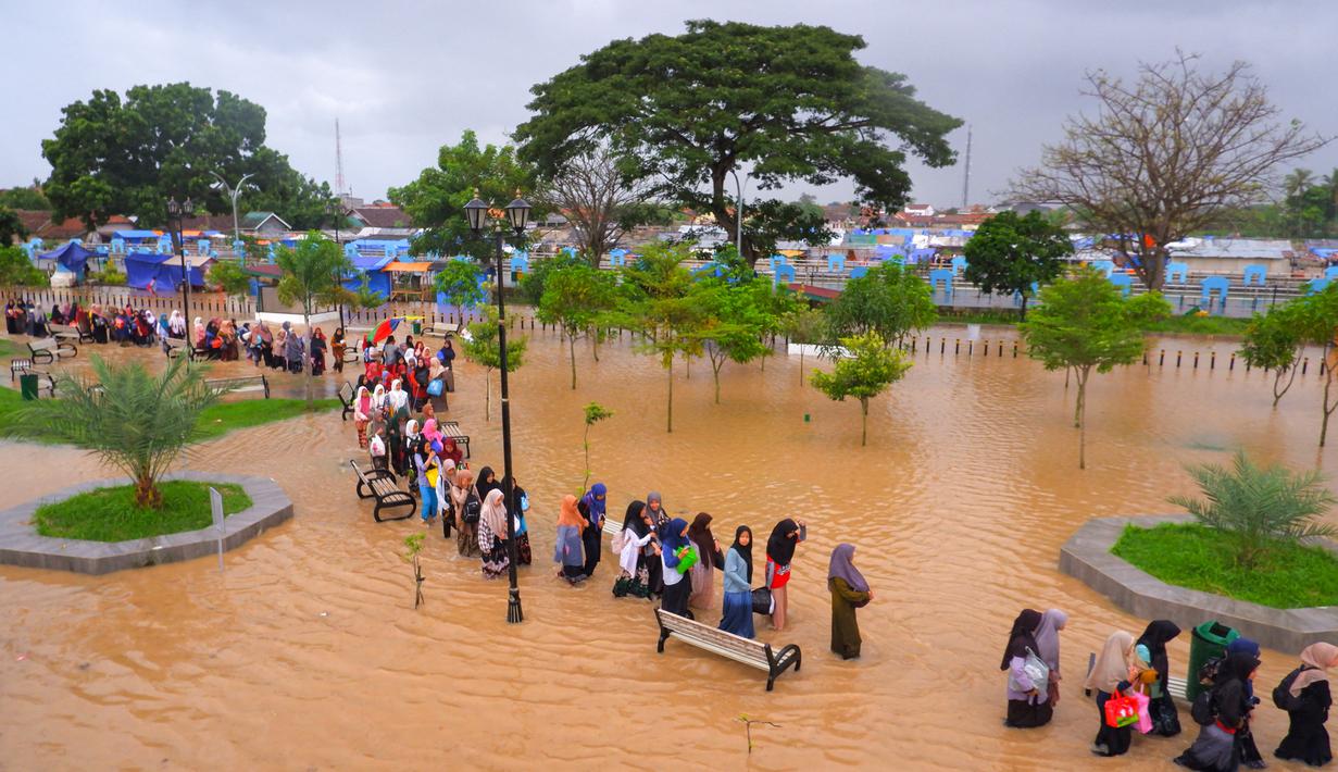 Warga mengarungi banjir saat mengungsi pasca banjir di Serang, Provinsi Banten (1/3/2022).  Banjir merendam Kota Serang akibat hujan deras yang turun sejak Senin malam (28/2/2022) hingga hari ini. (AFP/Dziki Oktomauliyadi)