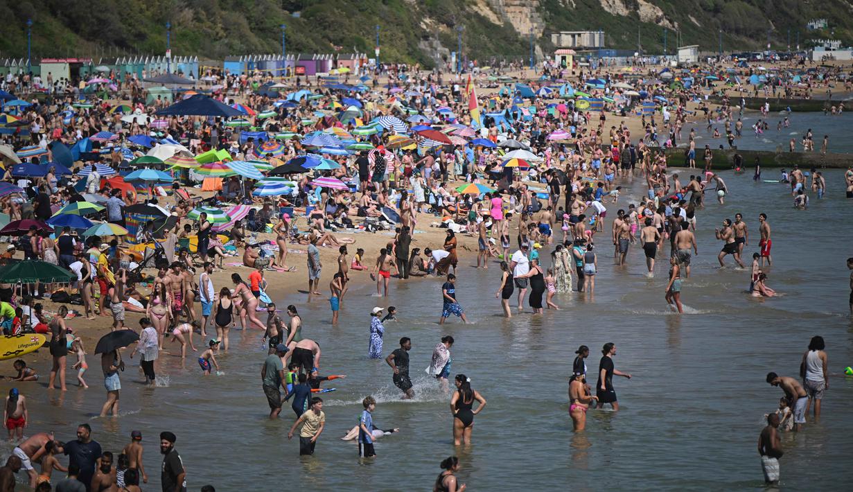 Para pengunjung bermain dan bersantai di bawah sinar matahari di Pantai Bournemouth, Selatan Inggris pada Selasa 26 Mei 2026, saat kondisi gelombang panas menyebar ke sebagian wilayah tenggara Inggris dan London. (JUSTIN TALLIS/AFP)