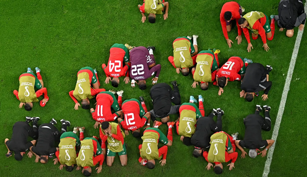Para pemain Maroko melakukan selebrasi pada akhir pertandingan babak 16 besar Piala Dunia 2022 menghadapi Spanyol di Education City Stadium, Al Rayyan, Rabu (6/12/2022) dini hari WIB. Aksi sujud syukur telah menjadi kebiasaan bagi para pemain Maroko di Piala Dunia 2022. (MANAN VATSYAYANA / AFP)