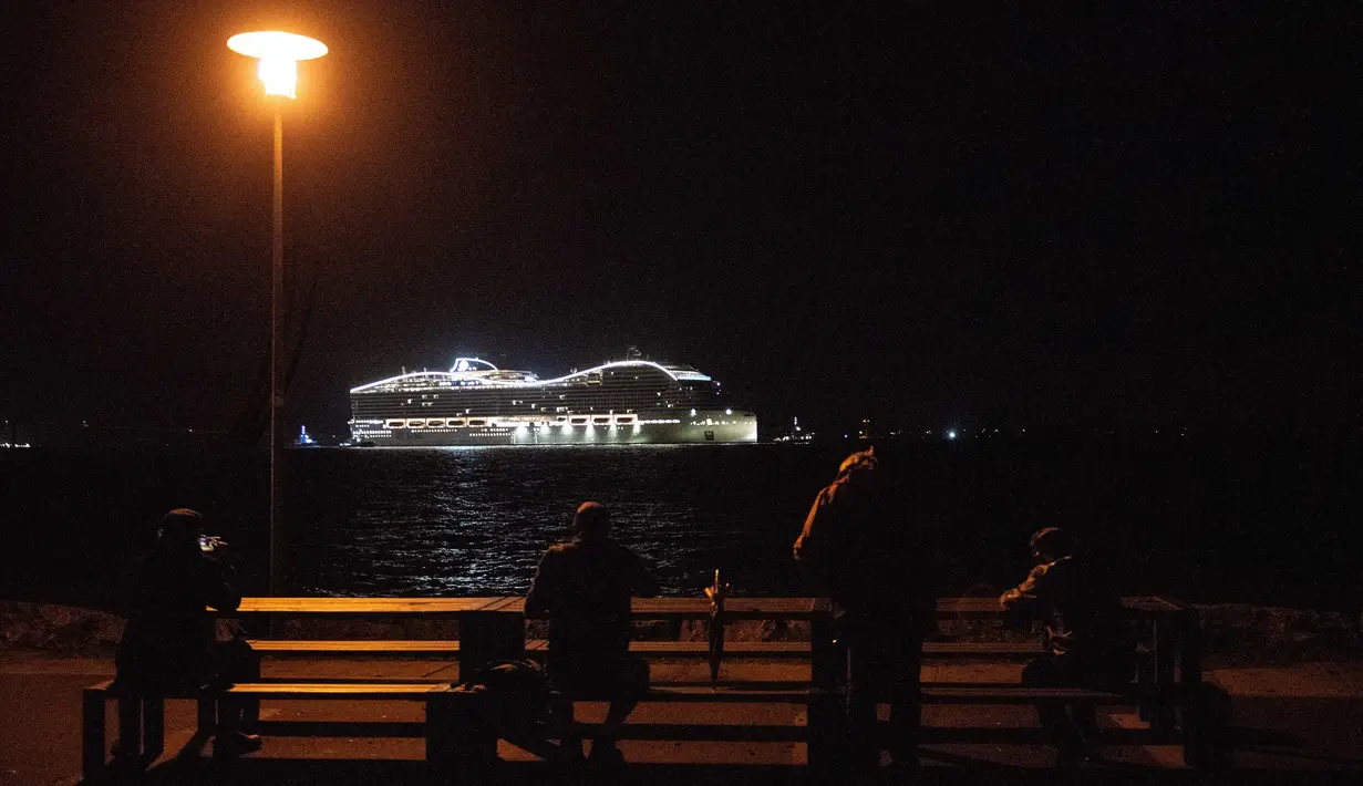 Warga menyaksikan kapal pesiar MSC World Europa meninggalkan pelabuhan Saint-Nazaire, Prancis barat pada 26 Oktober 2022.  MSC World Europa berlayar ke Qatar, di mana ia akan berfungsi sebagai hotel terapung selama Piala Dunia FIFA Qatar 2022. (AFP/Sebastien Salom Gomis)