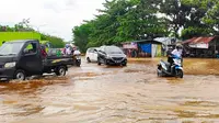 Warga mendorong sepeda motor karena mogok akibat nekat melintasi banjir di Pekanbaru. (Liputan6.com/M Syukur)
