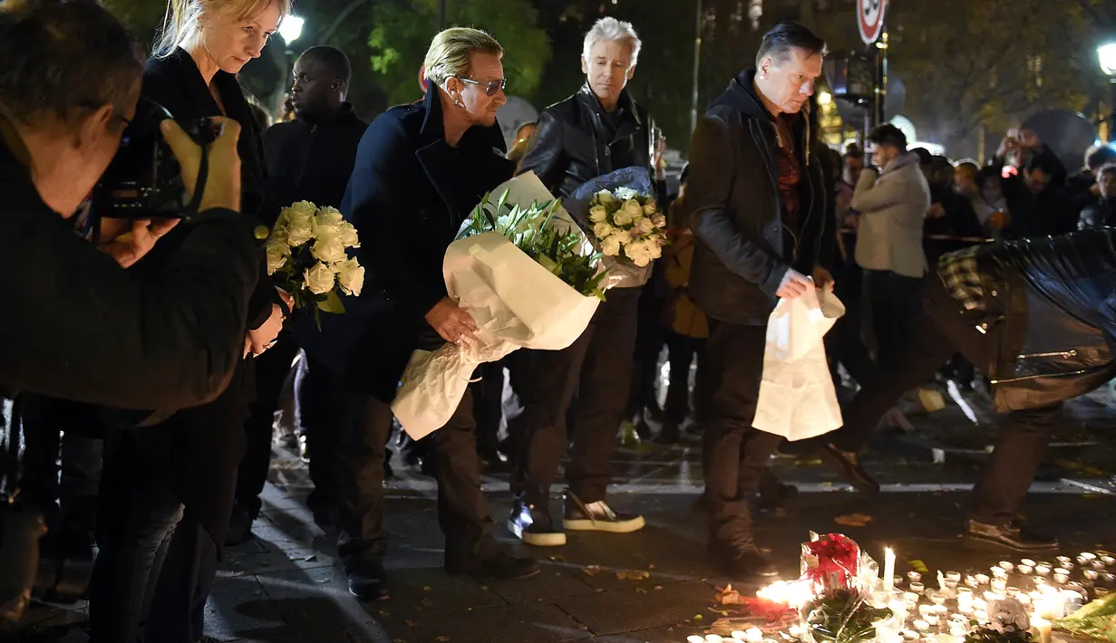 Grup band U2 Bono, Adam Clayton , Larry Mullen Jr  dan The Edge meletakkan karangan bunga di trotoar di depan gedung pertunjukan Bataclan Theatre, salah satu tempat serangan teroris di Paris, Perancis, Sabtu (14/11). (AFP PHOTO / FRANCK FIFE)