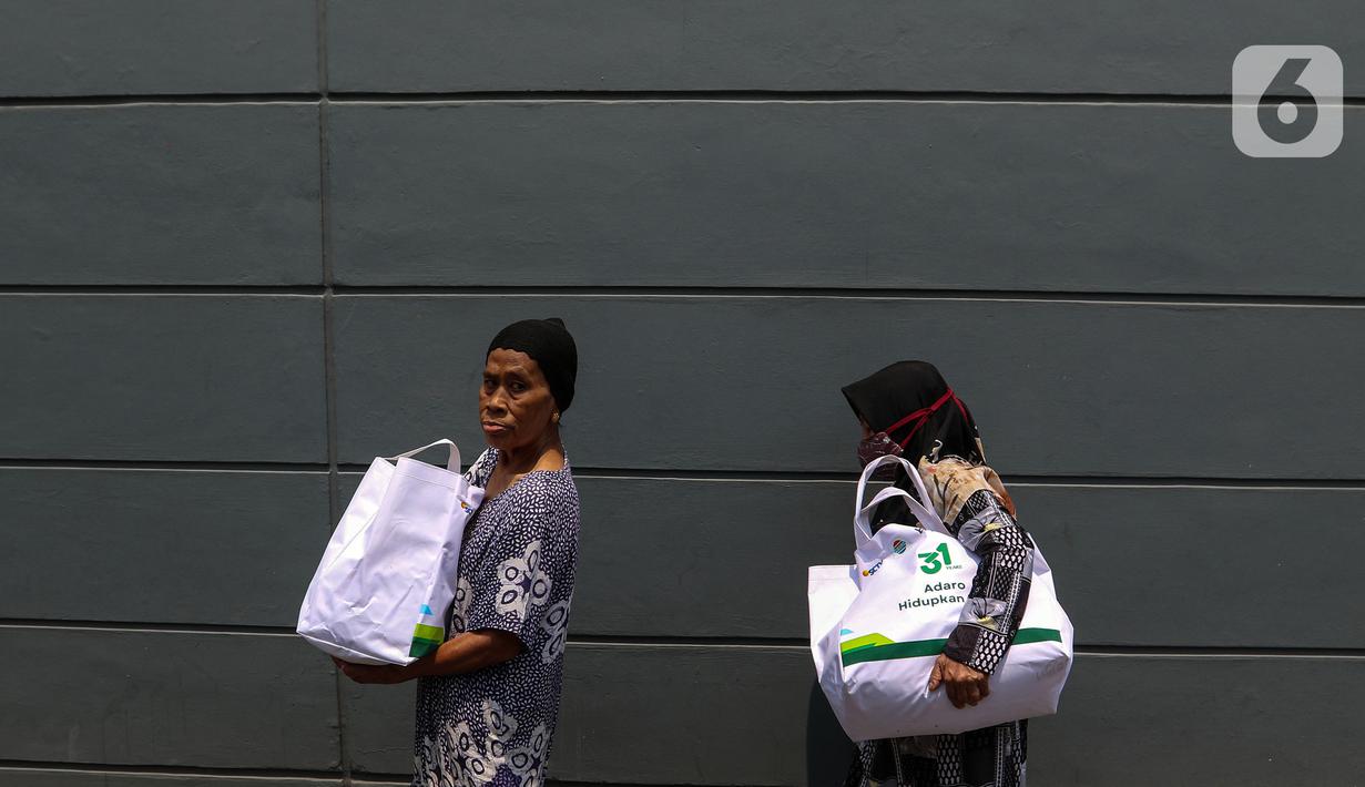 Warga membawa sembako yang di bagikan oleh PT Adaro Energi Tbk bersama Yayasan Pundi Amal Peduli Kasih (YPP) SCTV dan Indosiar di Jakarta, Rabu (4/10/2023). Dalam rangka Hari Ulang Tahun (HUT) Adaro ke-31 dengan tema “Adaro Hidupkan Hati” membagikan sembako sebanyak 2.000 paket  kepada masyarakat yang betul-betul memerlukan yang saat ini kurang beruntung di tengah beberapa harga sembako yang alami kenaikan. (Liputan6.com/Angga Yuniar)