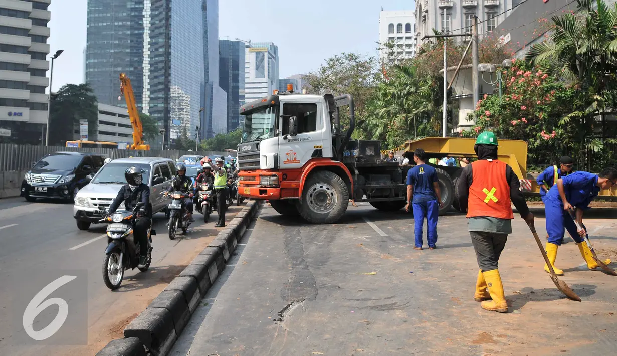 Petugas kepolisian mengatur lalu lintas akibat truk mengalami patah as di Jakarta, Selasa (29/9/2015). Imbas dari truk bermuatan alat berat mengalami patah as itu, Jalan Sudirman mengarah ke Jalan MH Thamrin terpantau padat. (Liputan6.com/Gempur M Surya)