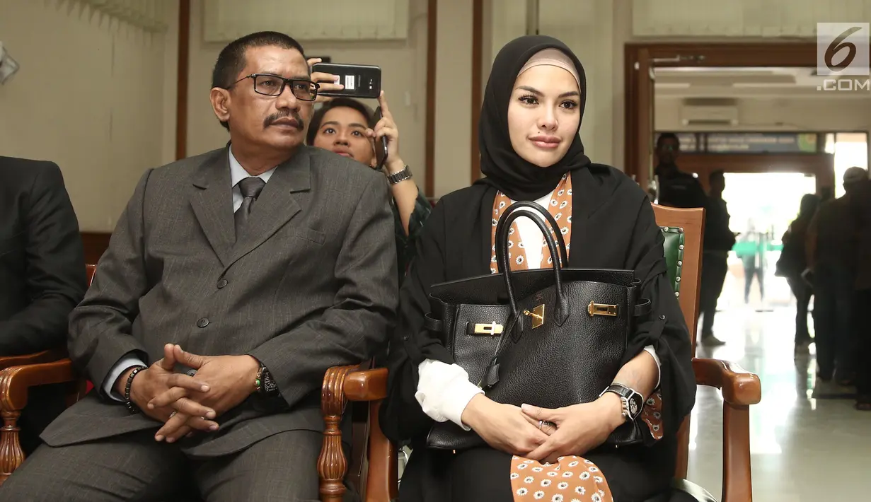 Aktris Nikita Mirzani (kanan) saat menjalani sidang isbat pernikahannya dengan Dipo Latief di Pengadilan Negeri Jakarta Selatan, Rabu (1/8). Nikita mengenakan gamis hitam dengan hijab warna senada. (Liputan6.com/Herman Zakharia)
