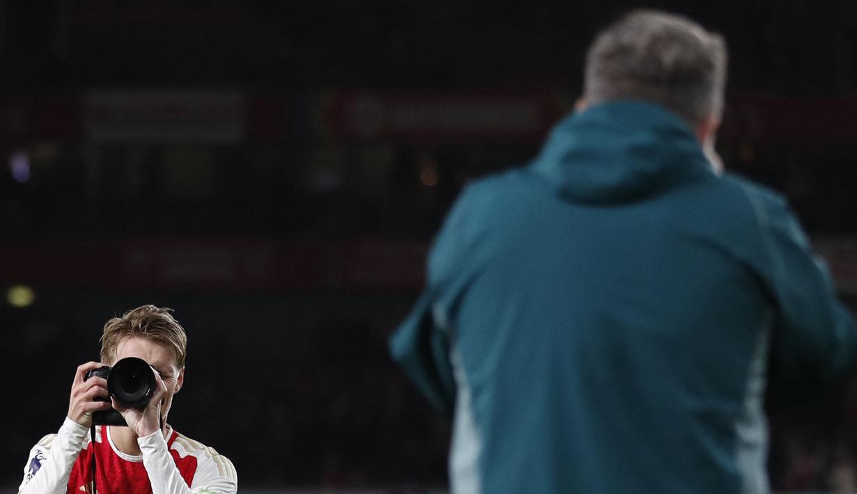 Pemain Arsenal, Martin Odegaard memotret salah satu fotografer ofisial tim setelah laga lanjutan Liga Inggris 2023/2024 melawan Liverpool di Emirates Stadium, London, Inggris, Minggu (05/02/2024) WIB. (AFP/Ian Kington)