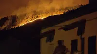 Kebakaran hutan yang berkobar di lereng bukit di atas desa Avelar, Portugal tengah, sebelum matahari terbit Minggu, 18 Juni 2017. (AP/Armando Franca)