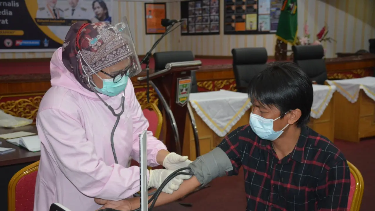 Ketua IJTI Sumbar, John Nedy Kambang melakukan cek kesehatan sebelum vaksinasi Covid-19. (Liputan6.com/ Humas Pemprov Sumbar).