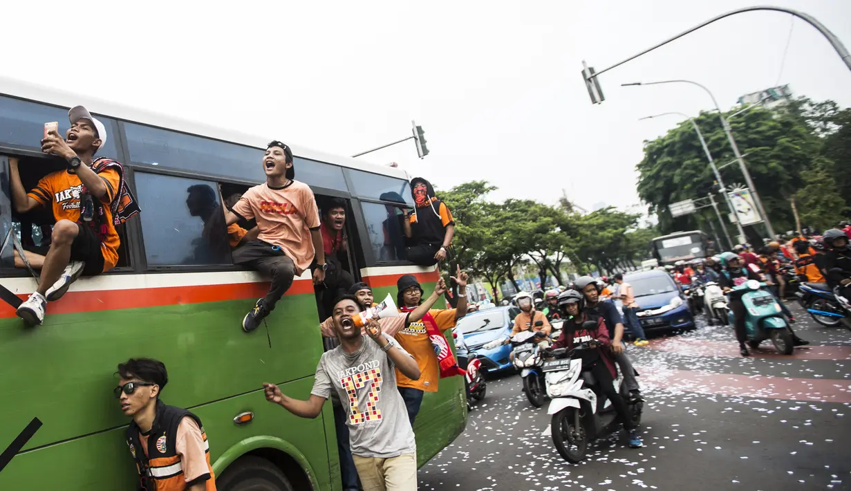 Suporter Persija Jakarta, The Jakmania, bernyanyi saat akan menonton laga Liga 1 melawan Mitra Kukar di Senayan, Jakarta, Minggu (9/12). Persija berpeluang besar menjadi juara jika berhasil menang. (Bola.com/Vitalis Yogi Trisna)