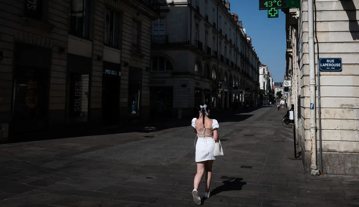<p>Seorang pejalan kaki berjalan di jalan saat tanda farmasi yang menyala menunjukkan suhu 43&deg;C, di Nantes, Senin (18/7/2022). Peramal cuaca menempatkan 15 departemen di sebagian besar sisi barat Prancis ke status siaga tertinggi untuk suhu ekstrem saat gelombang panas melanda negara itu dan akan mencapai puncaknya. (Loic VENANCE / AFP)</p>