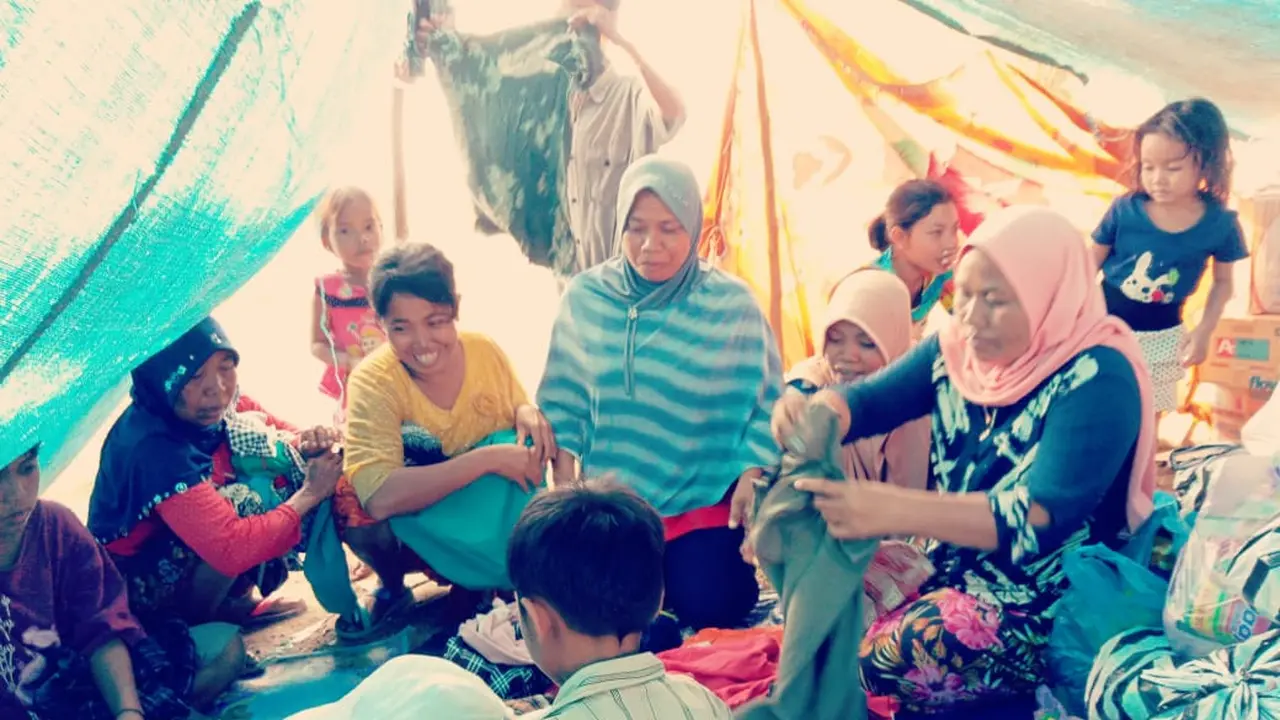 Wajah senang korban gempa Lombok di pengungsian saat menerima bantuan pakaian.