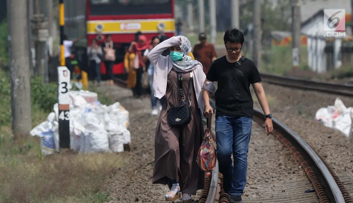 Sejumlah penumpang KRL Commuter Line terpaksa berjalan kaki menuju Stasiun Bojonggede, Bogor, Jawa Barat, Minggu (4/8/2019). Padamnya listrik di wilayah Jabodetabek mengakibatkan perjalanan KRL Commuter Line terhenti. (Liputan6.com/Helmi Fithriansyah)