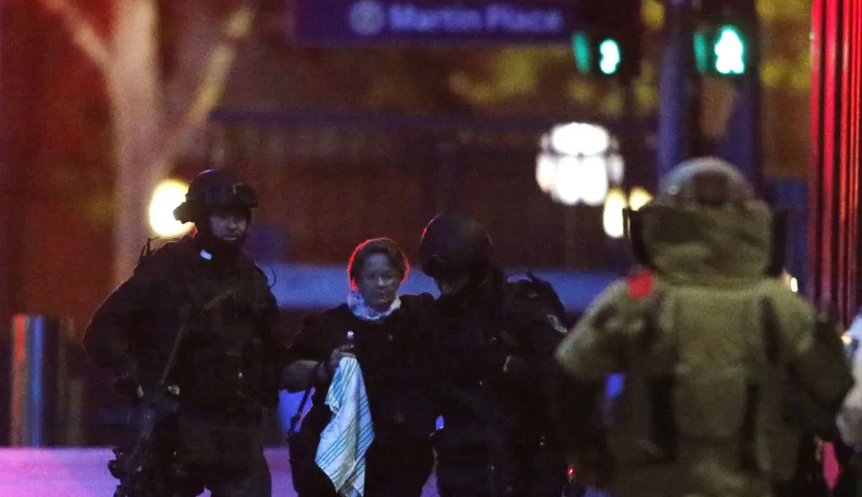 Dua petugas polisi bersenjata lengkap membantu sandera dari Kafe Lindt, Martin Place, Sydney (16/12/2014). (REUTERS/Jason Reed)