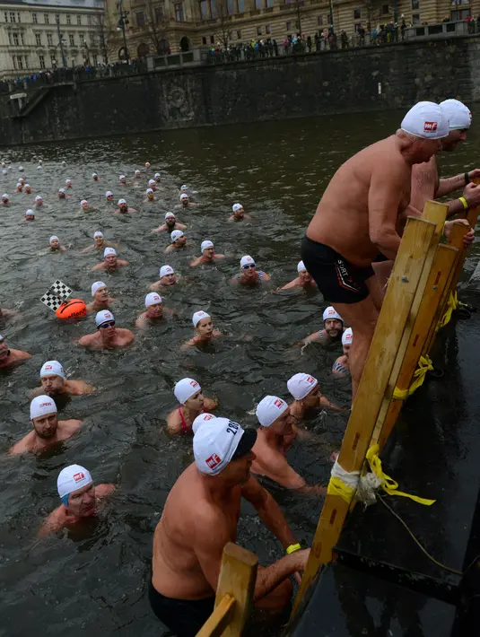 Orang-orang keluar dari sungai Vltava setelah mengikuti kompetisi berenang Natal tahunan, di ibu kota Republik ceko, Praha, Rabu (26/12). Dalam menyemarakkan Natal, mereka mengikuti lomba renang di sungai bersuhu dingin. (Michal CIZEK / AFP)