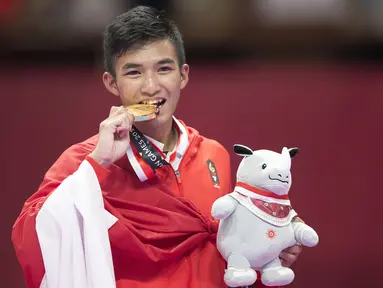 Karateka Indonesia, Rifki Ardiansyah Arrosyiid, menggigit medali usai beraksi pada Asian Games di JCC Senayan, Jakarta, Minggu (26/8/2018). Rifki berhasil medapat medali emas di nomor kumite 60 kilogram. (Bola.com/Peksi Cahyo)