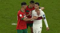 Pemain Timnas Portugal, Cristiano Ronaldo meninggalkan lapangan sambil dihibur dua pemain Timnas Maroko usai laga babak perempatfinal Piala Dunia 2022 di Al Thumama Stadium, Doha, Qatar, Sabtu (10/12/2022) malam WIB. (AP/Alessandra Tarantino)