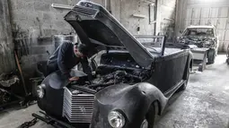 Munir Shindy mengecek mesin mobil tua di bengkelnya di Kota Gaza (28/10/2019).  Merestorasi mobil tua merupakan kegemarannya, namun sekarang Shindy kesulitan mendapat suku cadang yang dia butuhkan. (AFP Photo/Mahmud Hams)