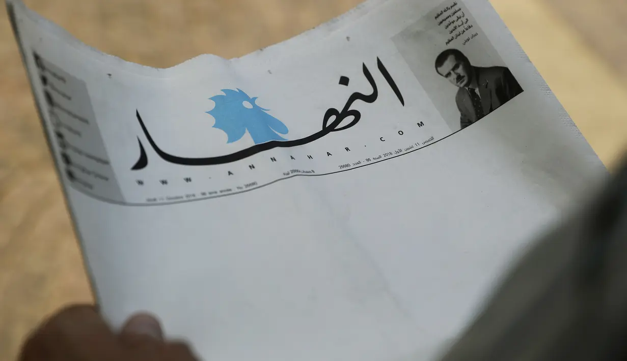 Seorang pria memegang surat kabar terkemuka Lebanon, An-Nahar, dengan halaman kosong tanpa berita di Beirut, Kamis (11/10). Surat kabar kosong itu sebagai protes atas situasi politik negeri yang tak kunjung membentuk pemerintahan baru. (AFP/JOSEPH EID)