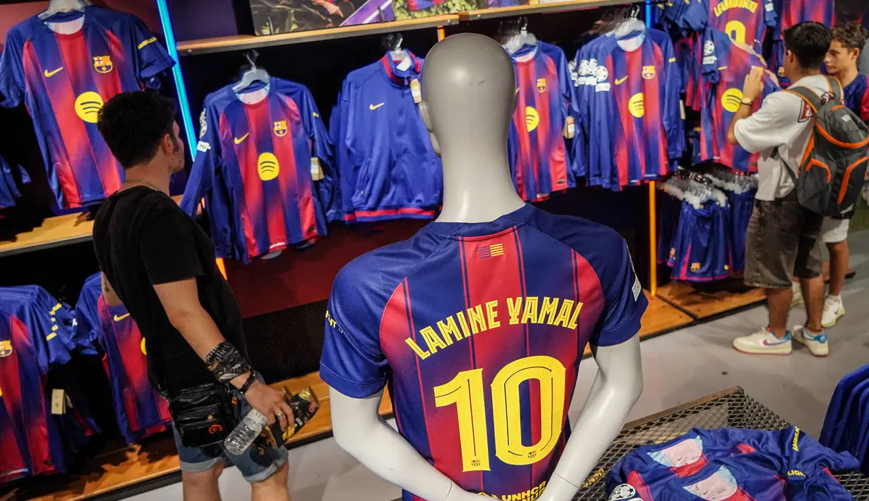 Pengunjung memilih jersey baru bernomor punggung 10 dari penyerang Barcelona asal Spanyol, Lamine Yamal di toko resmi FCB di Barcelona. (AFP/Manaure Quintero)