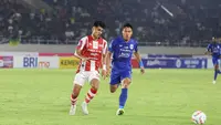 Penyerang Persis Solo, Ramadhan Sananta, saat tengah berebut bola dengan bek PSIS Semarang, Wahyu Prasetyo, pada laga bertajuk Derby Jawa Tengah di Stadion Manahan, Solo, Sabtu (16/9/2023). (Bola.com/Radifa Arsa)