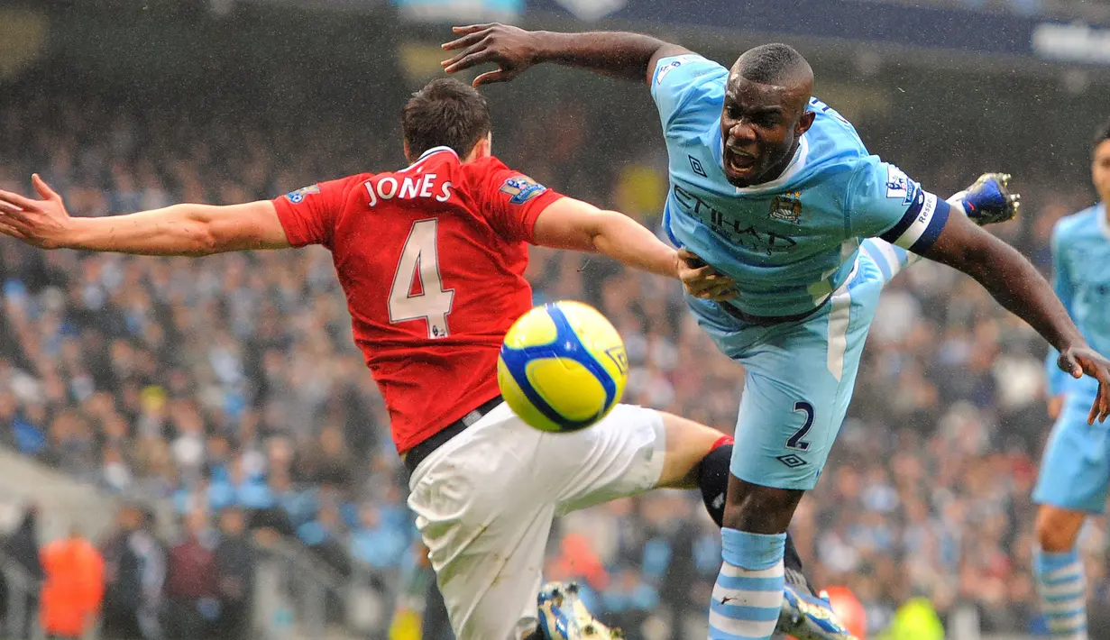 Pemain Manchester City, Micah Richards (kanan) berebut bola dengan pemain Manchester United, Phil Jones pada laga putaran ketiga Piala FA 2011/2012 yang berlangsung di Etihad Stadium, Manchester, 8 Januari 2012. (AFP/Andrew Yates)