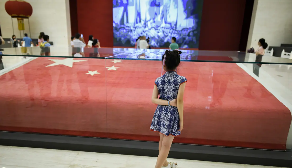 Seorang gadis melihat bendera nasional Tiongkok yang dikibarkan pada 1 Oktober 1949 di Lapangan Tiananmen di Museum Nasional China di Beijing (22/8/2019). Negara itu akan merayakan peringatan ke-70 berdirinya Pendirian Republik RakyatTiongkok pada tanggal 1 Oktober 2019. (AFP Photo/Wang Zhao)