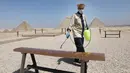 Pekerja menyemprotkan disinfektan di dekat Piramida Giza di Giza, 25 Agustus 2020. Mesir telah menerima 126.000 wisatawan sejak negara itu membuka kembali resor tepi lautnya untuk penerbangan internasional dan turis mancanegara pada 1 Juli, setelah ditutup akibat COVID-19. (Xinhua/Ahmed Gomaa)