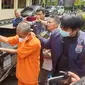 Tersangka AR tengah mempraktekan cara mencuri satu kendaraan pick up bermodalkan bambu tipis yang dibungkus lakban di depan wartawan di Mapolres Garut. (Liputan6.com/Jayadi Supriadin)