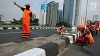 Petugas PSSU mengatur lalu lintas saat rekannya sedang mengecat  kembali  trotoar di Kawasan Jakarta, Selasa (1/8). Pengecatan dilakukan dalam rangka mempercantik wilayah yang disinergikan dengan menyambut HUT RI ke-72. (Liputan6.com/Helmi Afandi)