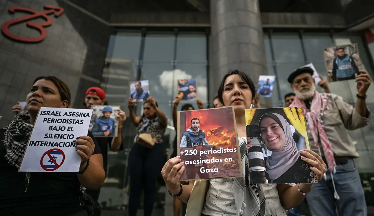 Di sisi lain, Israel justru menuduh salah satu dari mereka sebagai militan Hamas. Tampak dalam foto, para pekerja media pemerintah memegang potret jurnalis Palestina yang telah meninggal selama demonstrasi di depan gedung PBB di Caracas pada 11 Agustus 2025. (Juan BARRETO/AFP)