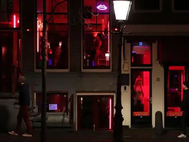 Orang-orang berjalan melewati rumah bordil di Red Light District Amsterdam, Belanda, Rabu (3/4). Red Light District merupakan kawasan prostitusi yang tersohor dan menjadi salah satu destinasi wisata di Belanda. (REUTERS/Yves Herman)