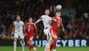 Striker Bosnia and Herzegovina, Edin Dzeko, berduel memperebutkan bola dengan pemain Wales pada playoff Piala Dunia 2026. (Darren Staples / AFP)