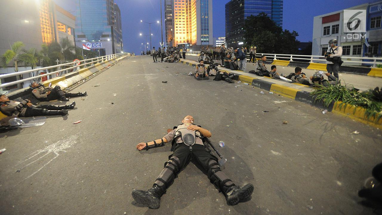 Anggota Dalmas BKO dari Polda Bali beristirahat usai mengamankan perusuh di atas fly over Slipi, Jakarta, Rabu (22/5/2019). Bentrokan panjang dengan para perusuh membuat anggota kepolisian yang berhadapan langsung kurang beristirahat.