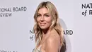 <p>Sienna Miller berpose saat tiba untuk acara National Board of Review Awards Gala di Cipriani 42nd Street di New York City pada 8 Januari 2023. Miller mengenakan rambut pirang mudanya yang dibelah di tengah dan mengalir ke bawah dalam gelombang lembut. (Jamie McCarthy/Getty Images for National Board of Review/AFP)</p>