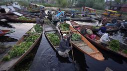 Laki-laki Kashmir menjual produk mereka di pasar sayuran terapung di Danau Dal, Srinagar, Kashmir yang dikuasai India, Kamis (7/4/2022). (AP Photo/Rajesh Kumar Singh)