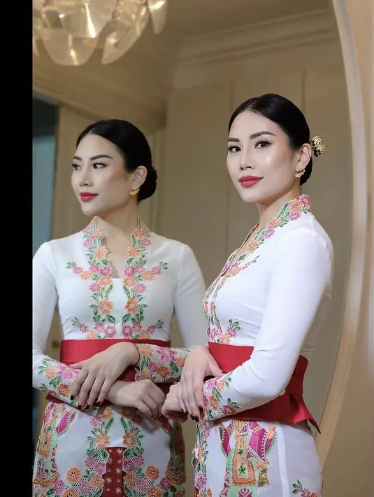 Angela tampil dengan makeup glam, MUA Lorita Young memoles wajahnya dengan blush on pink, lipstik merah bold matte, dan riasan mata shimmernya. Ia juga mengenakan cat kuku hitam. [Instagram/@loritayoung_mua]