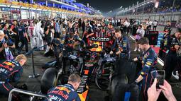 Tim Red Bull Racing sedang mempersiapkan mobil Max Verstappen sebelum melakukan balapan pada Formula 1 GP Qatar 2025 di Sirkuit Lusail, Lusail, Qatar, Minggu (30/11/2025) waktu setempat. (AFP/Andrej Isakovic)