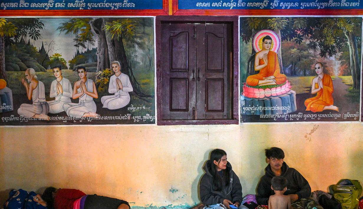 Warga beristirahat di dalam kuil setelah dievakuasi menyusul bentrokan di sepanjang perbatasan Kamboja-Thailand, di provinsi Siem Reap, pada Selasa 9 Desember 2025. Ribuan warga dievakuasi ke tempat perlindungan di sepanjang perbatasan Kamboja dengan Thailand, seiring meletusnya kembali konflik bersenjata antara kedua negara. (TANG CHHIN SOTHY/AFP)