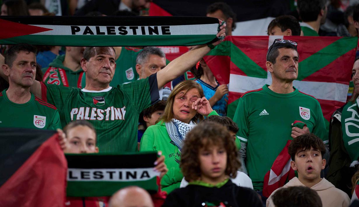 Diketahui, sejak 7 Oktober 2023, pasukan Israel melancarkan operasi ekstensif di Jalur Gaza yang berimbas pada beragam krisis kemanusiaan, termasuk kelaparan, penghancuran, pengungsian dan penangkapan. Tampak dalam foto, para pendukung mengibarkan bendera Palestina dan bendera wilayah Basque Utara selama pertandingan persahabatan antara tim pemain Palestina dan sekelompok pemain Spanyol dari wilayah Basque, yang diadakan sebagai protes terhadap aksi militer Israel di Gaza, di Bilbao, Spanyol, Sabtu 15 November 2025. (AP Photo/Miguel Oses)