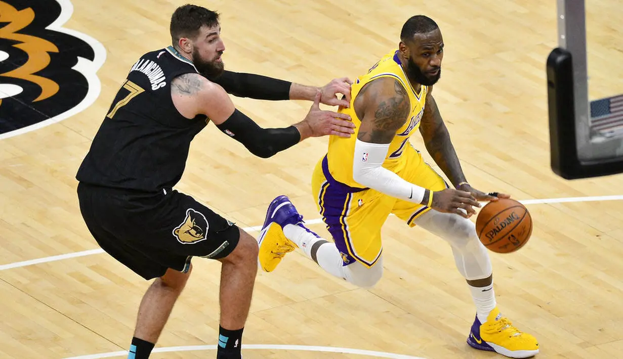 Pebasket Los Angeles Lakers, LeBron James, berusaha melewati pebasket Memphis Grizzlies, Jonas Valanciunas, pada laga NBA, Rabu (6/1/2021). LA Lakers menang tipis 94-92 atas Grizzlies. (AP Photo/Brandon Dill)