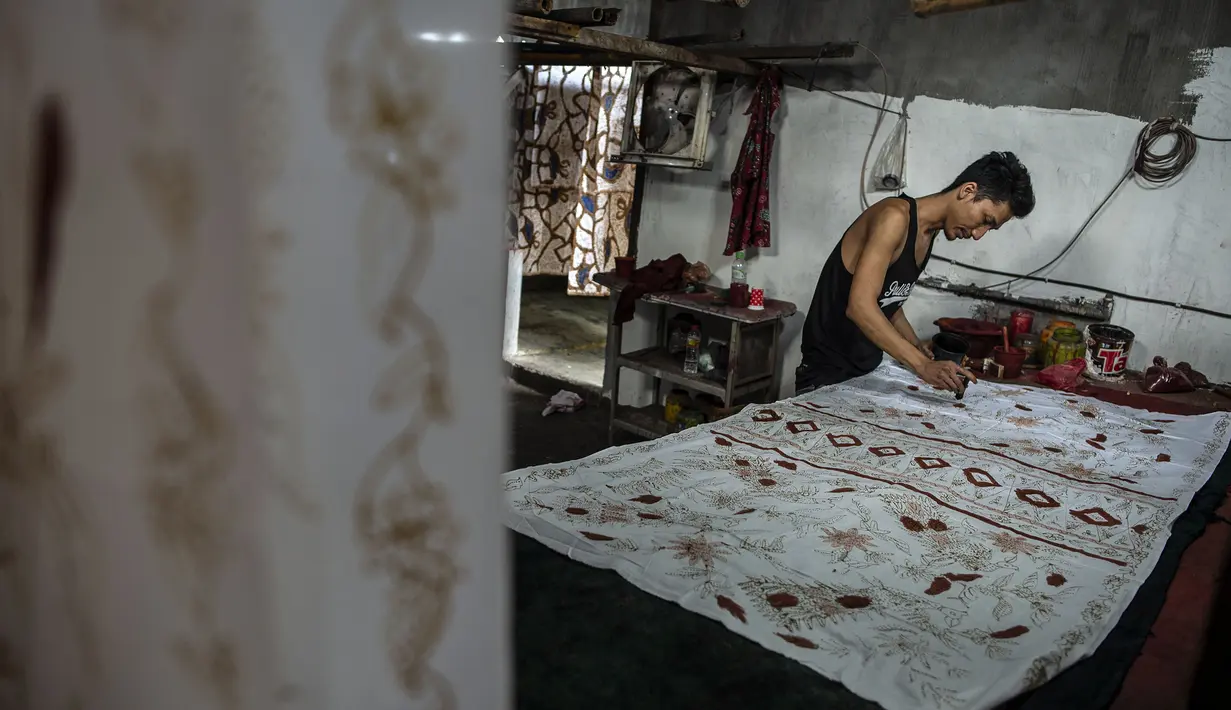Seorang pekerja mensketsa batik di pabrik "batik" kain tradisional Indonesia di Sidoarjo, Jawa Timur (12/11/2019). UNESCO menetapkan batik sebagai karya agung lisan dan warisan budaya takbenda kemanusiaan. (AFP Photo/Juni Kriswanto)