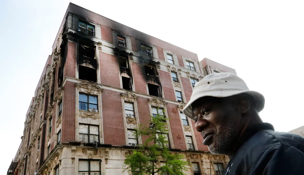 Penghuni apartemen yang terbakar memeriksa lokasi kejadian di kawasan Harlem, New York, AS, Rabu (8/5/2019). Keenam korban tewas yang masih satu keluarga diketahui bernama Andrea Pollidore (45), Mac Abdularaulph (33), Nakiyra (11), Andre (8), Brooklyn (6), dan Ellijah (4). (AP Photo/Richard Drew)