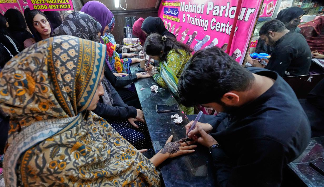 Tradisi henna (atau lebih dikenal sebagai Mehndi dalam bahasa Urdu) di Pakistan merupakan bagian tak terpisahkan dari perayaan budaya, terutama dalam pernikahan dan hari raya keagamaan. Tampak dalam foto, para penata kecantikan, di sebelah kiri, melukis 'Henna' tradisional di tangan pelanggan untuk perayaan Idul Fitri, yang menandai berakhirnya bulan suci Ramahan, di Rawalpindi, Pakistan, Rabu, 18 Maret 2026. (AP Photo/Anjum Naveed)