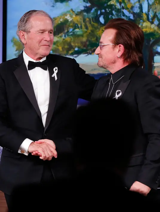 Presiden AS ke-43 George W. Bush berjabat tangan vokalis U2 Bono selama gala untuk Forum Kepemimpinan di Institut George W. Bush di Dallas, AS (19/4). Dalam acara ini Bush mempersembahkan Bono medali Distinguished Citizenship. (AP Photo/Brandon Wade)