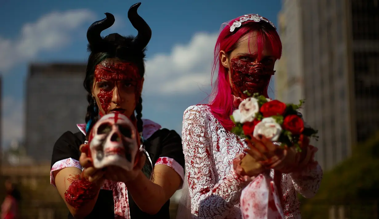 Dua orang perempuan mengenakan kostum dan dandanan menyerupai zombie selama acara Zombie Walk di Sao Paulo, Brasil, Sabtu (2/11/2019). Ratusan orang turun ke jalan memakai kostum karakter horor pada acara tahunan yang digelar sejak 2006 pada Hari Para Arwah. (Miguel SCHINCARIOL / AFP)