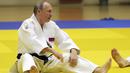 Presiden Vladimir Putin melakukan pemanasan sebelum mengikuti sesi latihan judo bersama atlet nasional Rusia di Sochi, Kamis (14/2). Judo merupakan salah satu olahraga kegemaran Putin yang telah digeluti sejak masa muda. (Mikhail KLIMENTYEV/SPUTNIK/AFP)
